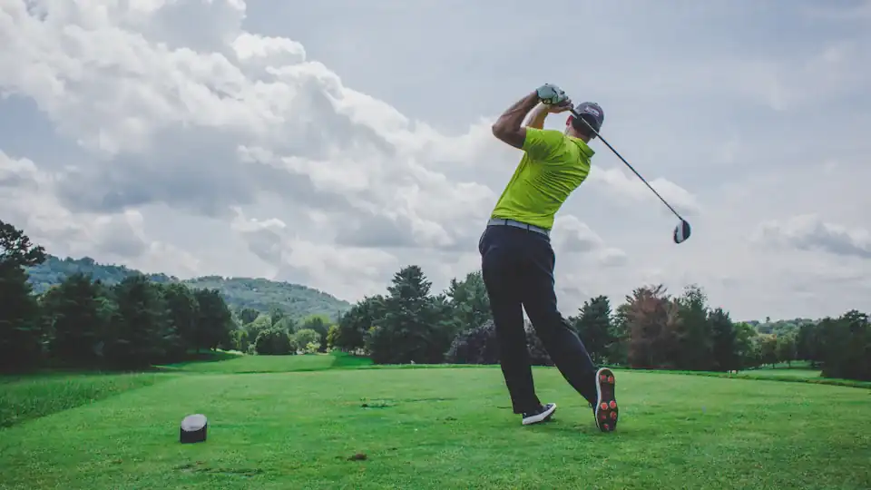 Golfer completing a swing on an elevated tee