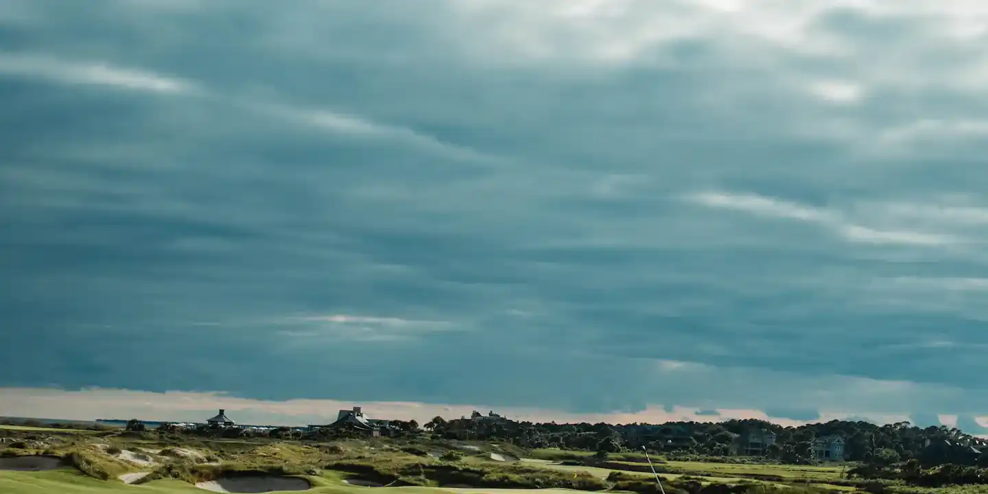Golfer walking off a links green past a deep bunker