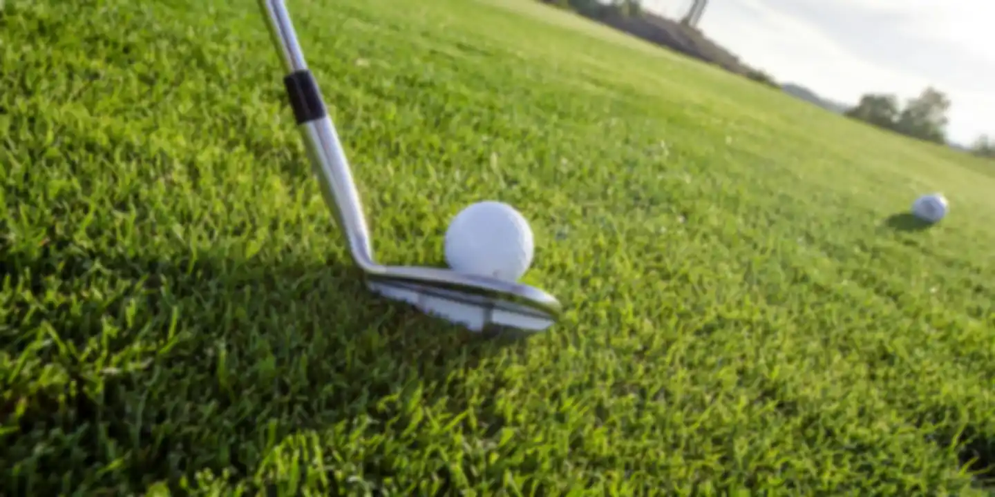 Wedge and golf ball on a closely mown fairway